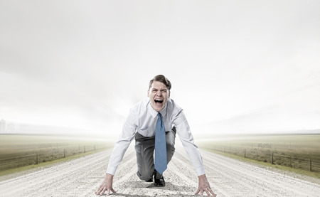 Young determined businessman in starting position ready to competeの写真素材