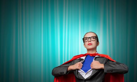 Businesswoman wearing red cape and opening her shirt like superheroの写真素材