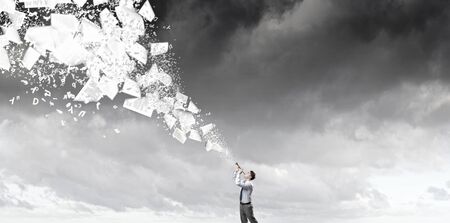 Young businessman playing flute and papers flying outの写真素材