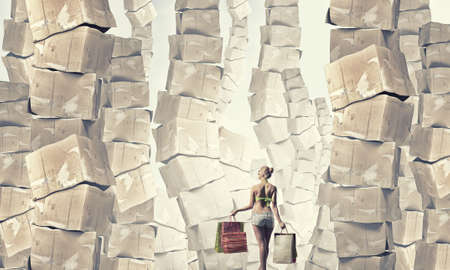 Beautiful young girl in bikini with shopping bags and pile of carton boxesの写真素材