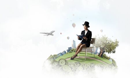 Pretty girl wearing retro hat siting on chair with book in handsの写真素材