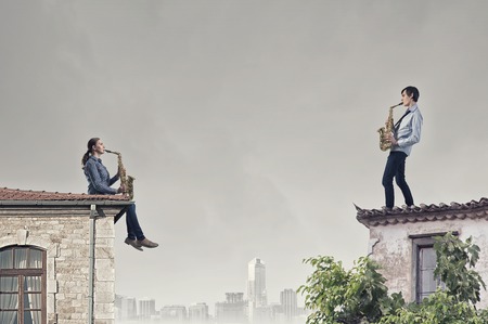 Duet of young man and woman musicians playing saxophonesの写真素材