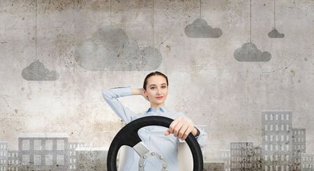 Young smiling pretty woman driving steering wheelの写真素材