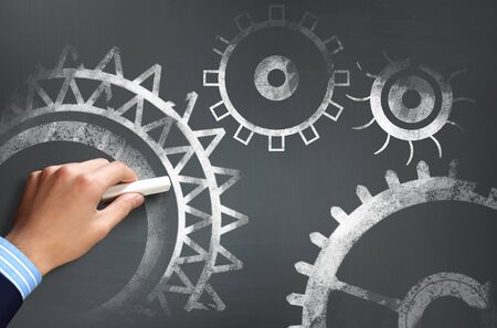 Businessman hand drawing with chalk gears mechanism as teamwork conceptの写真素材