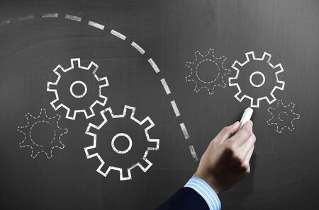 Businessman hand drawing with chalk gears mechanism as teamwork conceptの写真素材