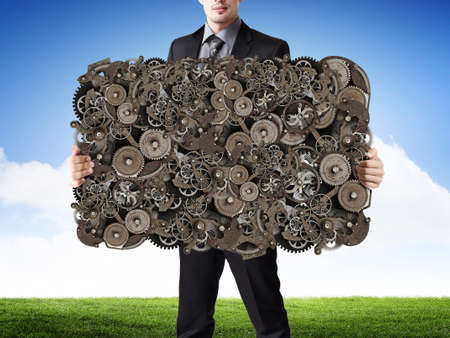 Businessman holding gears mechanism as teamwork conceptの写真素材