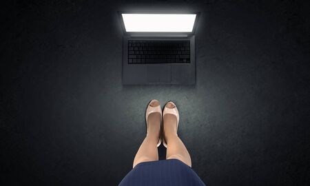 Top view of businesswoman feet and laptop on floorの写真素材