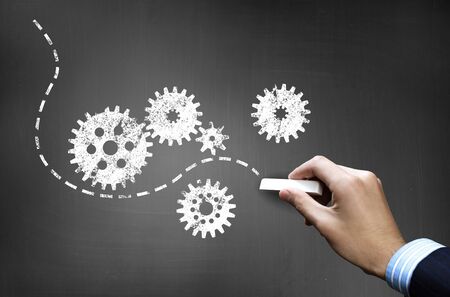 Businessman hand drawing with chalk gears mechanism as teamwork conceptの写真素材