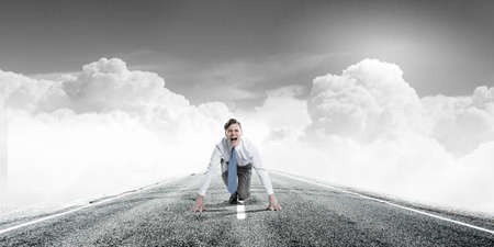 Young determined businessman in starting position ready to competeの写真素材