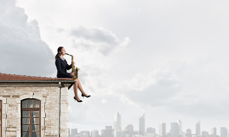 Young woman in suit with saxophone in handsの写真素材