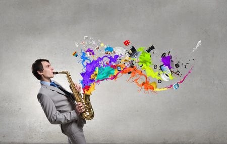 Young man playing saxophone and paint splashes coming outの写真素材