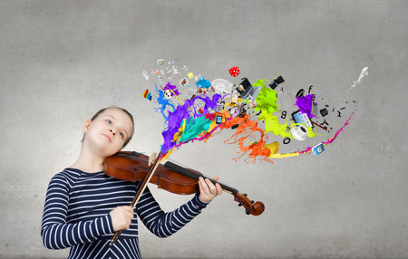 Cute kid girl playing violin and colorful splashes flying outの写真素材