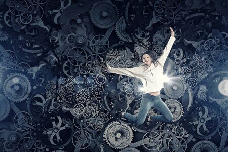 Young woman dancer jumping in spotlights on gears background