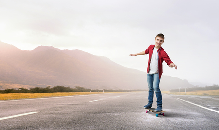 Handsome teenager cool acive boy riding skateboardの写真素材