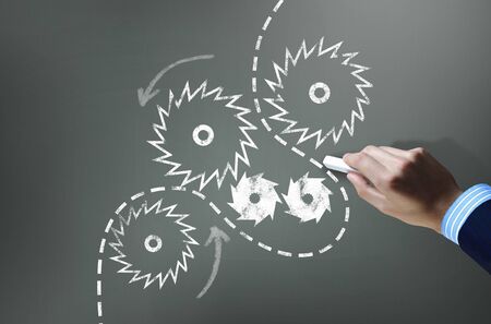 Businessman hand drawing with chalk gears mechanism as teamwork conceptの写真素材