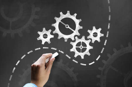 Businessman hand drawing with chalk gears mechanism as teamwork conceptの写真素材