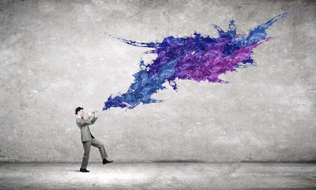 Young businessman in black hat playing fluteの写真素材