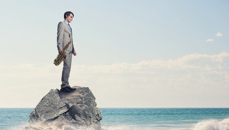 Young man in suit with saxophone in handsの写真素材