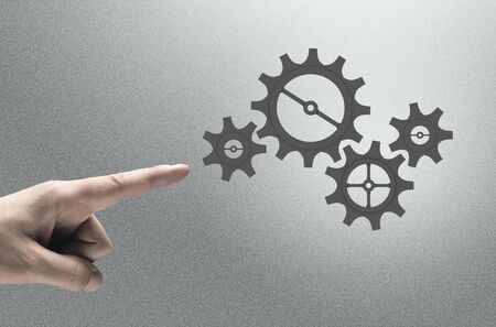 Close up human hand pointing with finger at gears mechanism
