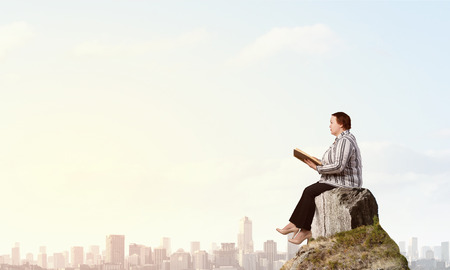 Plus size woman sitting with book in handsの写真素材