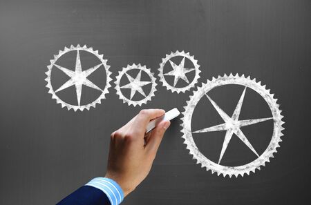 Businessman hand drawing with chalk gears mechanism as teamwork conceptの写真素材