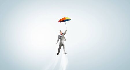 Businessman flying in sky on colorful umbrellaの写真素材