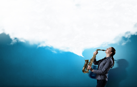 Young woman playing saxophone and cloud coming outの写真素材