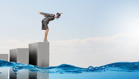 Young businesswoman in suit and diving mask jumping in waterの写真素材