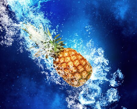 Fresh pineapple in clear blue water splashesの写真素材