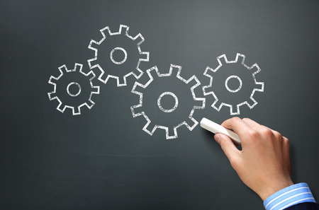 Businessman hand drawing with chalk gears mechanism as teamwork conceptの写真素材