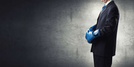 Young businessman in boxing gloves on dark backgroundの写真素材