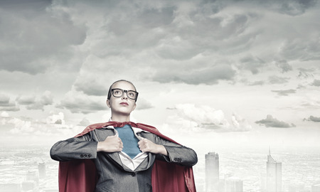 Businesswoman wearing red cape and opening her shirt like superheroの写真素材