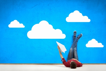 Young man lying on floor with legs raised upの写真素材