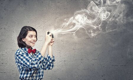 Young beautiful woman taking photo with retro camera