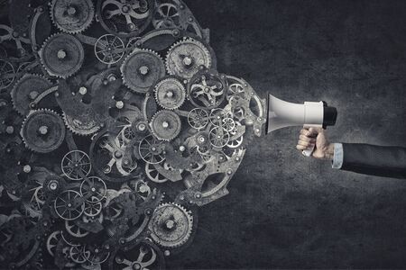 Hand of businessman with megaphone and gears mechanismの写真素材