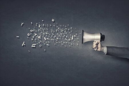 Businessman hand with loudspeaker and characters flying outの写真素材
