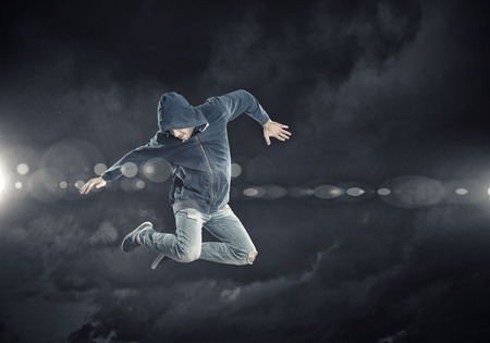 Modern style male dancer jumping in lights of spotlight