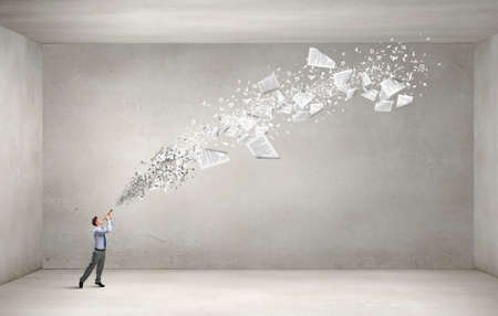 Young businessman playing flute and papers flying outの写真素材