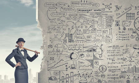 Young pretty woman in suit and hat with baseball batの写真素材