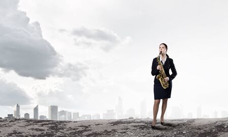 Young woman in suit with saxophone in handsの写真素材