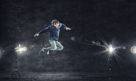 Modern style male dancer jumping in lights of spotlightの写真素材