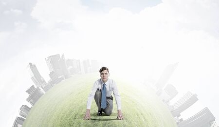 Young determined businessman in starting position ready to competeの写真素材