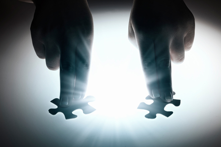 Hand connecting two jigsaw glowing puzzle piecesの写真素材