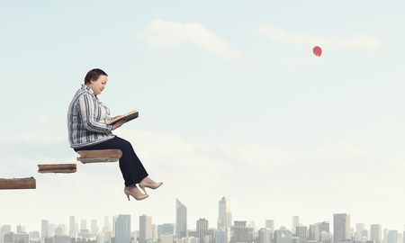 Plus size woman sitting with book in handsの写真素材