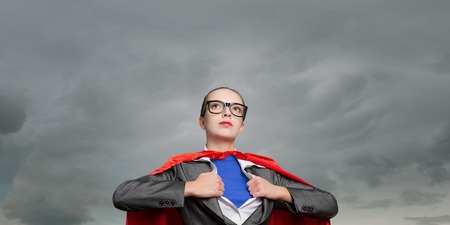 Businesswoman wearing red cape and opening her shirt like superheroの写真素材