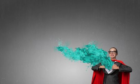 Businesswoman wearing red cape and opening her shirt like superheroの写真素材