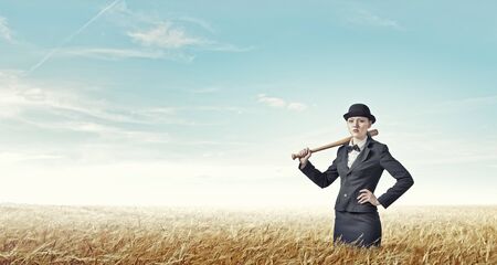 Young pretty woman in suit and hat with baseball batの写真素材