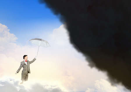 Businessman standing with umbrella under black cloudの写真素材
