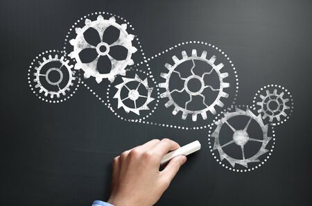 Businessman hand drawing with chalk gears mechanism as teamwork conceptの写真素材