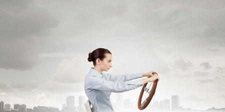Young smiling pretty woman driving steering wheelの写真素材